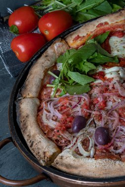 Geleneksel İtalyan pizzası roka, kurutulmuş domates, mozarella ve soğanlı ve siyah zeytinli biberli dilimler.
