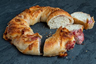 İtalyan doğal mayalanmış ekmeği, İtalyan peyniri ve Calabrese sosisi ile doldurulmuş. Koyu arkaplanda