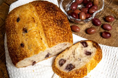 Ev yapımı lezzetli doğal fermantasyon ekmeği ve siyah zeytin. Beyaz bez peçete ve ahşap masa üzerinde