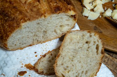 Ev yapımı lezzetli, peynirli doğal fermantasyon ekmeği. Beyaz bez peçete ve ahşap masa üzerinde