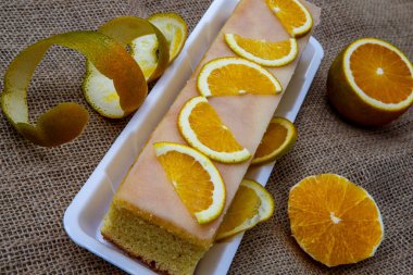 Üzerinde taze portakal dilimleri ve jute kanvas arka planı olan turuncu pasta..