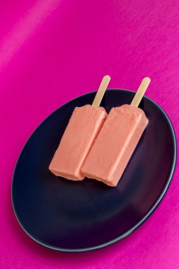 Mavi tabak ve fuşya arka planında eriyen böğürtlen dondurması. Boşluk