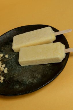 Turuncu arka planda mısır taneleri olan sarı mısır çubukları tabakada eriyor. Metin uzayı