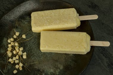 Koyu arkaplanda mısır taneleriyle plakada eriyen sarı mısır çubukları..