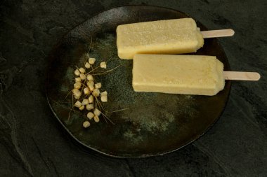 Koyu arkaplanda mısır taneleriyle plakada eriyen sarı mısır çubukları..