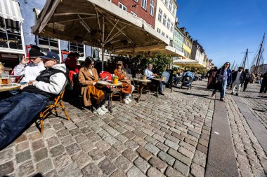 Kopenhag, Danimarka - Nisan 02, 2025 - 17. yüzyıldan kalma renkli evleri, barları, kafeleri ve restoranları olan Nyhavn 'da insanlar geziniyor..