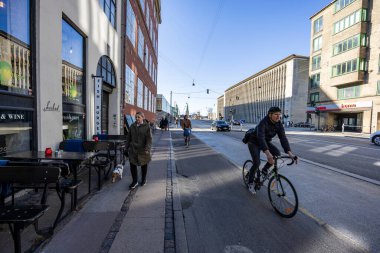 Bisiklet yolunda bisiklet süren insanlar. Kopenhag 'da şehir caddesinde bisiklet trafiği. Danimarka 'da sürdürülebilir ulaşım ve modern şehir hayatı kavramı. Kopenhag, Danimarka - 31 Mart 2025