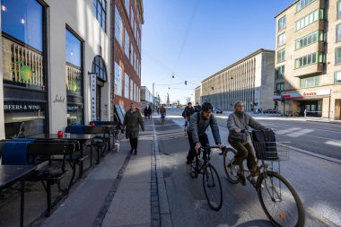 Bisiklet yolunda bisiklet süren insanlar. Kopenhag 'da şehir caddesinde bisiklet trafiği. Danimarka 'da sürdürülebilir ulaşım ve modern şehir hayatı kavramı. Kopenhag, Danimarka - 31 Mart 2025
