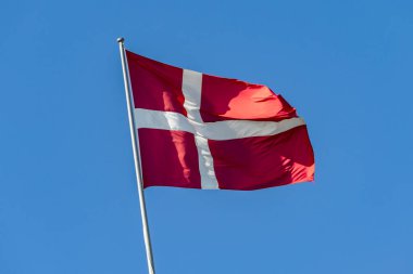 Mavi gökyüzü arka planında Danimarka bayrağı. Rüzgarda dalgalanan Danimarka bayrağı.