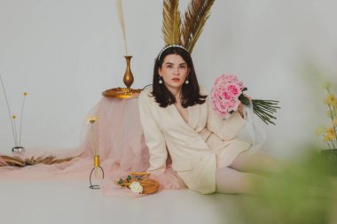 Beyaz ceketli ve beyaz taytlı güzel esmer kız elinde bir buket gül tutuyordu.