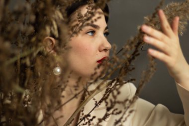 Siyah saçlı ve kuru çiçekli güzel bir kadın. Güzel surat. Fotoğraf stüdyoda çekildi.