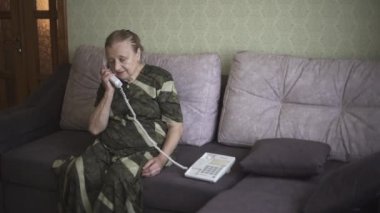 Büyükannem bir telefon açar ve onunla duygusal olarak konuşur. Yaşlı kadın konuştuğu birinden bilgi almakta zorlanıyor..