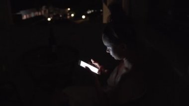 Kız, zaman çizelgesini gece telefonda kaydırıyor. Genç bayan geceleri internette geziniyor..