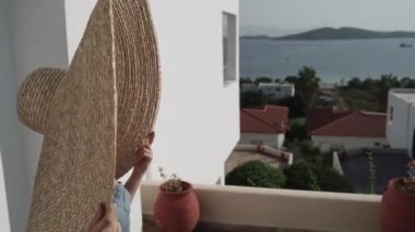 Genç ve güzel bir kadının büyük bir şapka ve gözlük takıp etrafa bakındığı bir fotoğraf. Büyük şapkalı bir kadının denize bakarken orta pozu..