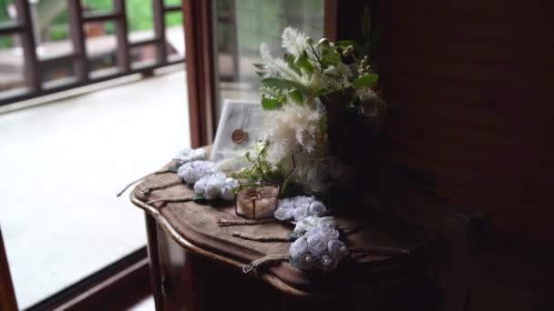 Una foto de los detalles de la boda. Bonitos boutonnieres con flores. Joyero con anillos en la mesa. Increíble ramo para la novia en un día especial — Vídeos de Stock