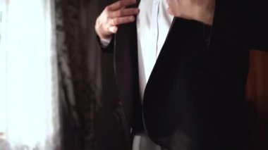 Önemli bir olaya hazırlanan bir adamın orta pozu. Damat tören için hazırlanıyor. Beyaz gömlekli adam siyah ceketini giyiyor..