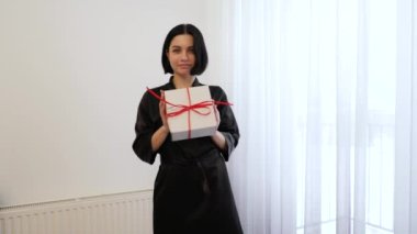 Elinde hediye kutusu olan genç bir bayan. Elinde hediye tutan güzel bir esmer kız. Evde hediyesiyle mutlu bir kadın. Orta resim, online alışveriş.