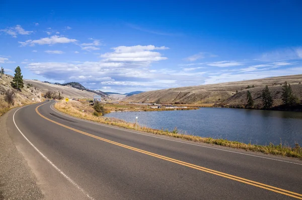 Tranquil Lake Between Road and Hills Royalty Free Stock Images