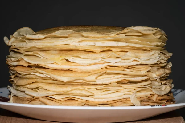 Beyaz tabakta yüksek miktarda kızarmış krep ve koyu gri arka plan