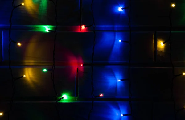 Luces verticales navideñas en habitación oscura. Amarillo, verde, rojo, azul — Foto de Stock