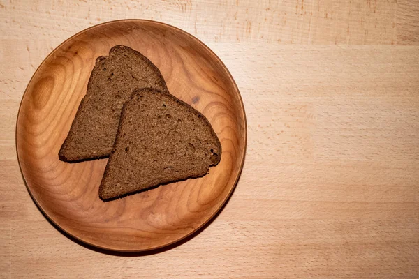Dois pedaços de pão triangular granulado preto em chapa redonda de madeira — Fotografia de Stock