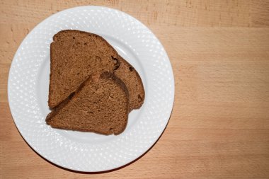 Üç parça siyah üçgen ekmek beyaz tabakta izole edilmiş.