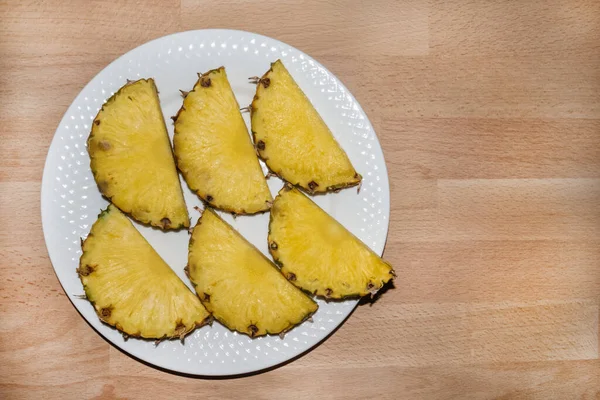 Seis pedaços de abacaxi cortados em uma placa branca — Fotografia de Stock