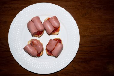 Dört küçük sandviç, yanında sosis ve ketçap. Koyu renk ahşap