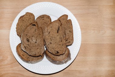 Beyaz tabakta yedi parça koyu çavdar ekmeği.