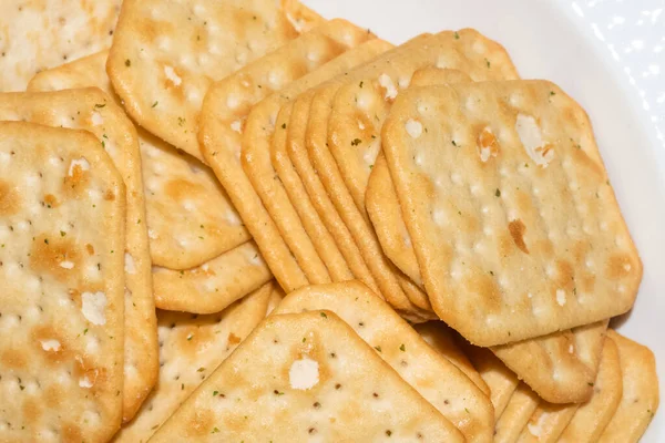 Macro sparatoria di cracker speziati croccanti su piatto bianco — Foto Stock