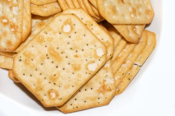 Gros plan de croustilles jaunes carrées avec de petits trous sur plat blanc — Photo