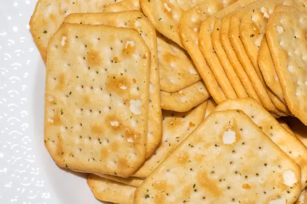 Porzione satura di cracker quadrati croccanti e speziati su piatto bianco — Foto Stock