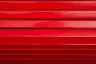 Yatay eğimli kırmızı tahta levhaların üzerine yağmur damlaları konur.