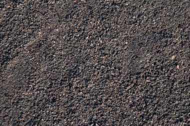 Kuru desenli kara toprak ve güneşin altında küçük kayalar.