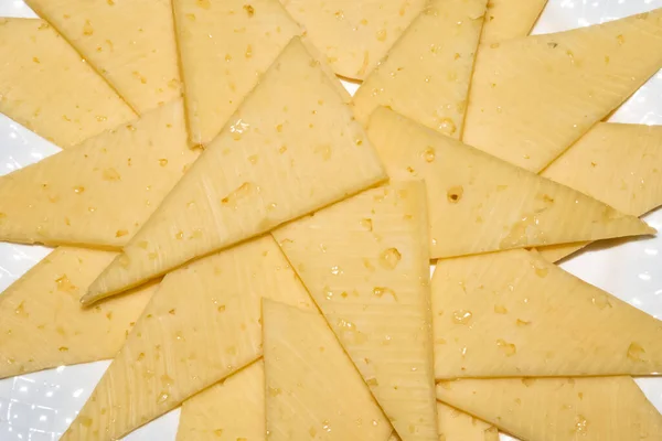 Krojony trójkąt żółte kawałki sera na białym talerzu — Zdjęcie stockowe