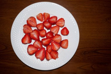 Beyaz tepside şekerle kaplı olgun kesilmiş çilekler.