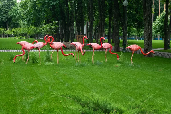 Kharkiv, Ucrânia - 6 de junho de 2021. Dez estátuas de flamingo vermelho decorativo em diferentes poses na grama verde no Central Park — Fotografia de Stock