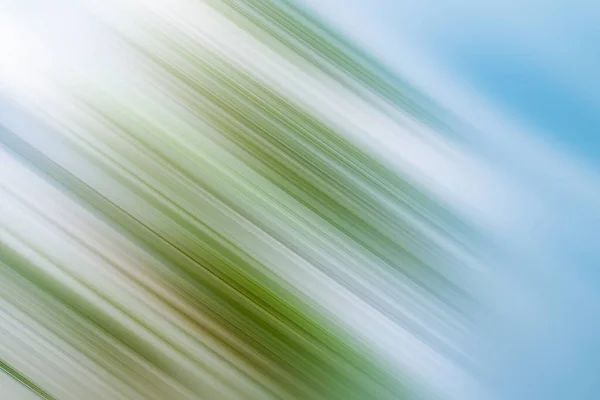 Bright falling green motion on blue blurred backdrop. Sun flare in the left corner — Stock Photo, Image