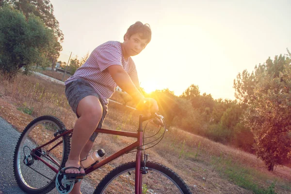 Pojke Poserar Cykel Utomhus Vid Solnedgången Royaltyfria Stockbilder