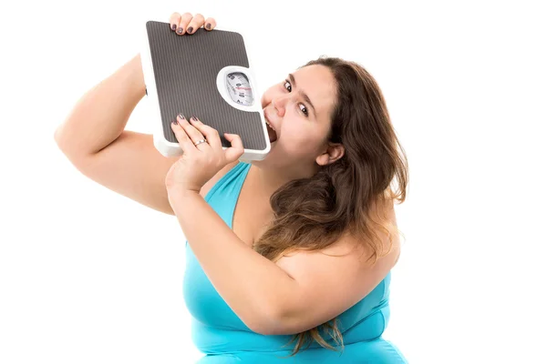 Large girl biting a weight scale — Stock Photo, Image