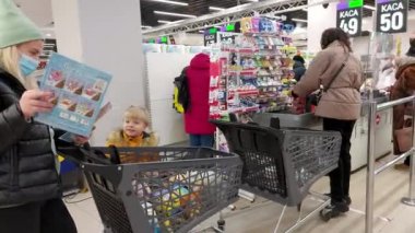 Avrupa, Kiev, Ukrayna - Kasım 2020: Bakkal arabalı maskeli bir kız Covid-19 Coronavirus salgını sırasında kentin süpermarketlerinden birinde ödeme yapıyor. Süpermarket çıkışı.