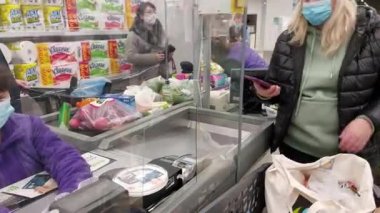 Avrupa, Kiev, Ukrayna - Kasım 2020: Bakkal arabalı maskeli bir kız Covid-19 Coronavirus salgını sırasında kentin süpermarketlerinden birinde ödeme yapıyor. Süpermarket çıkışı.