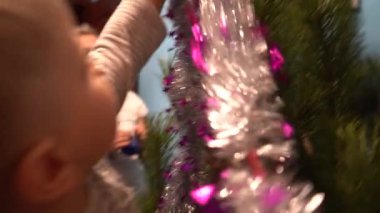 Avrupa, Ukrayna, Kiev - Aralık 2020: Noel ağacı süslemesi. Çocuklu bir anne yeni yıl ağacını süslüyor. Apartmandaki canlı bir çam ağacında güzel yeni yıl oyuncakları.