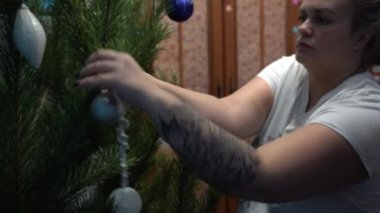 Avrupa, Ukrayna, Kiev - Aralık 2020: Noel ağacı süslemesi. Çocuklu bir anne yeni yıl ağacını süslüyor. Apartmandaki canlı bir çam ağacında güzel yeni yıl oyuncakları.