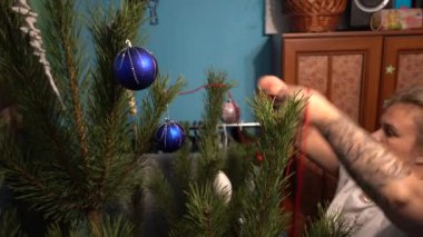 Avrupa, Ukrayna, Kiev - Aralık 2020: Noel ağacı süslemesi. Çocuklu bir anne yeni yıl ağacını süslüyor. Apartmandaki canlı bir çam ağacında güzel yeni yıl oyuncakları.