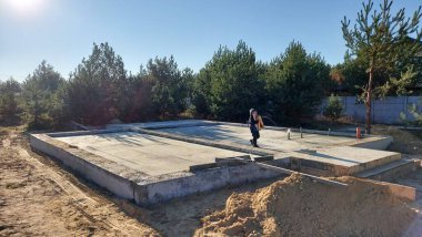 Özel bir kulübenin inşaatı. Gelecekteki evin temelleri çam ağaçları arasında..