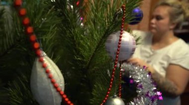 Avrupa, Ukrayna, Kiev - Aralık 2020: Noel ağacı süslemesi. Çocuklu bir anne yeni yıl ağacını süslüyor. Apartmandaki canlı bir çam ağacında güzel yeni yıl oyuncakları.