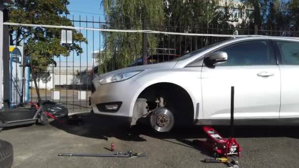 Europe, Ukraine, Kiev - Octobre 2020 : Voiture sans roue à la station technique. Jack sous la voiture. Montage des pneus — Video