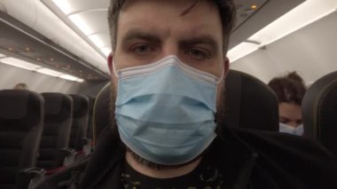 Covid-19 Coronavirus salgını sırasında uçakta uçmak. Uçaktaki maskeli adam. Yakın plan..