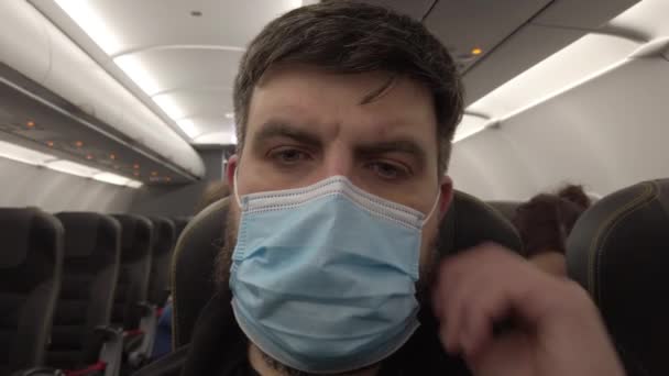 Vol en avion pendant la pandémie de coronavirus Covid-19. Un homme masqué dans l'avion. Gros plan. — Video